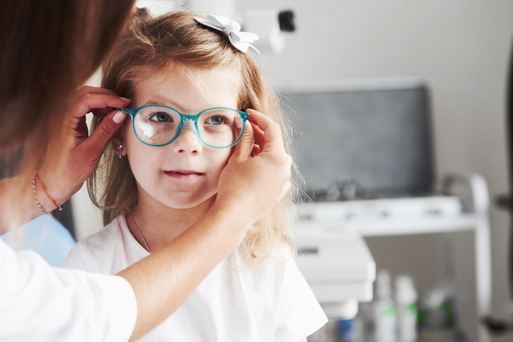 New look. Doctor giving the child new glasses for her vision