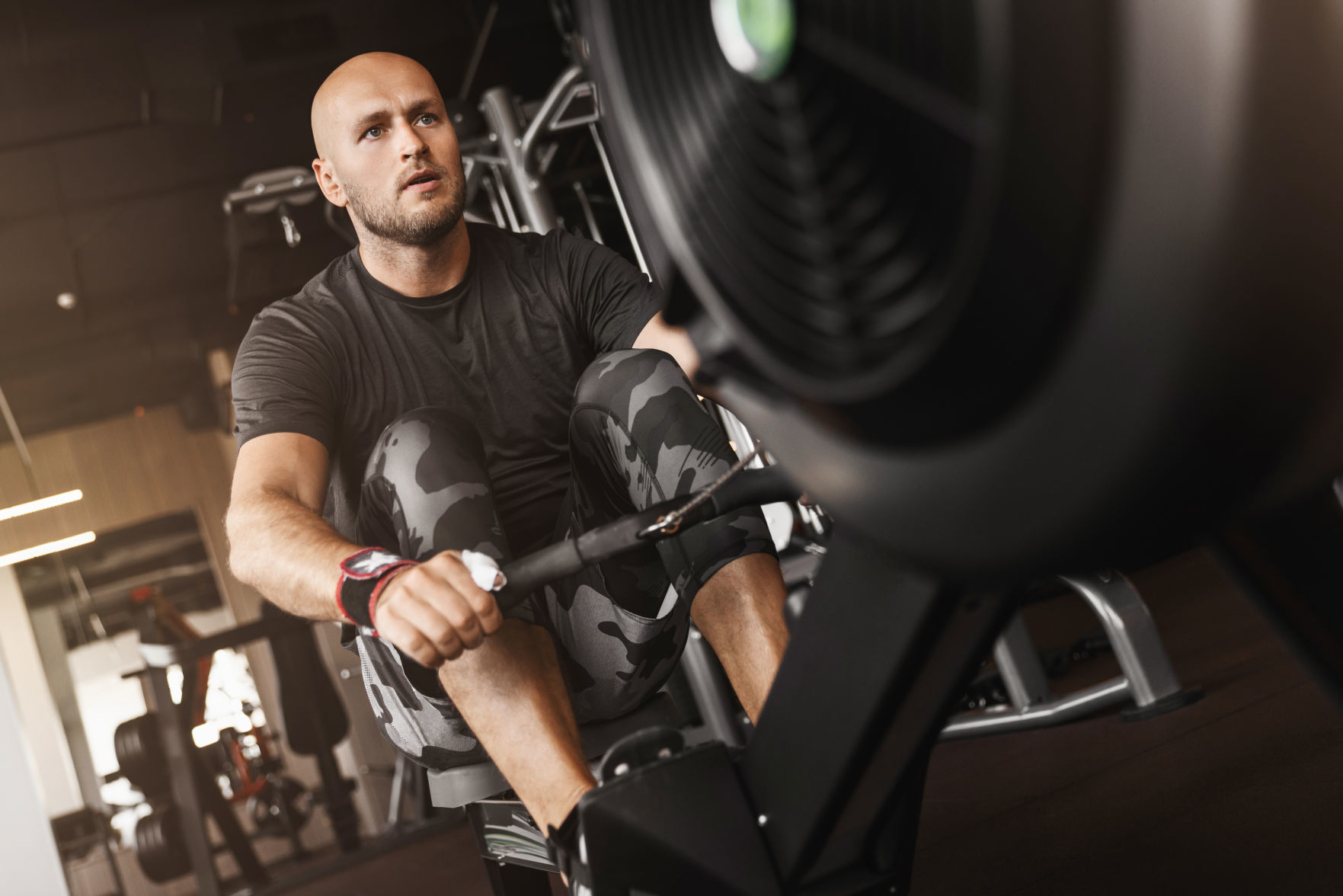 Fitness caucasian young adult man using rowing machine in the gym for fit training