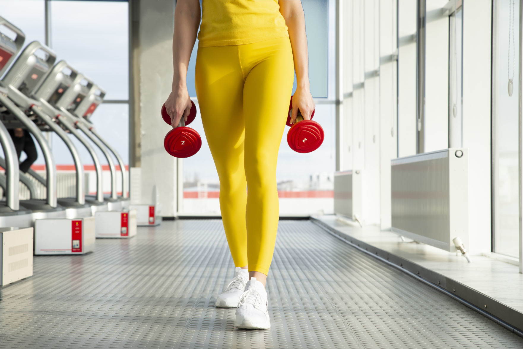 Physically fit woman at the gym with dumbbells ready to strengthen her arms and biceps